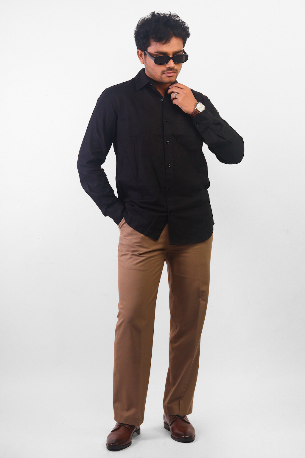 Handsome man wearing a black shirt and brown pants, hand in pocket standing  against a white background looking at camera. Stock Photo | Adobe Stock